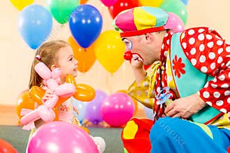Happy child girl playing with clown on birthday