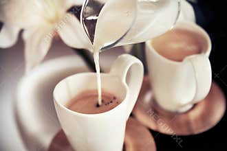 Two cups of coffee with decoration and poured milk