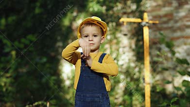 Portrait of kid boy builder wearing protective yellow helmet looking at camera. Little boy engineer builder architect