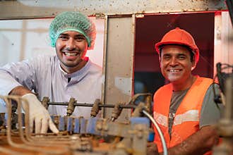 Two smiling senior and young engineers working in production line food and beverage factory industry