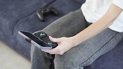 Close-up of a teenager's hands with a phone and a game jostick