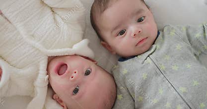 Cute little newborn twins babies boy and girl lying together in bed at home.