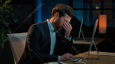 Night office businessman working computer late overwork tired exhausted sick middle-aged Caucasian man relieving eye