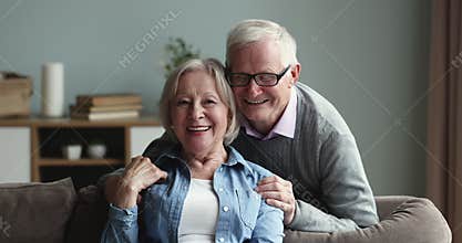 Cheerful older couple looking at camera with toothy smiles