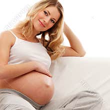 A happy blond pregnant woman sitting on a sofa