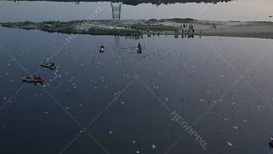 Aerial video of people feeding birds on a fishing boat along the Yamuna river in New Delhi, India.