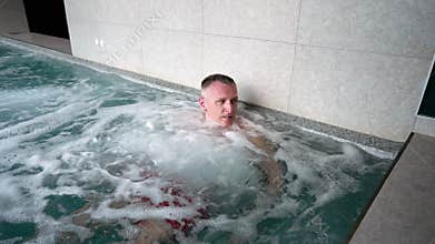 A man relaxes in a jacuzzi pool.