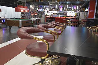 Empty retro bar interior with red bar stools and pool tables