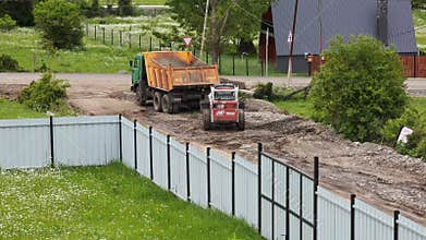 Skid steer loader unloading dirt into dump truck