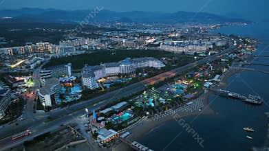 Stunning aerial sunset to night transition over Turkler in Alanya, Turkey. Alanya coastline,resorts,marina,hotels and city lights