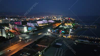 Stunning aerial sunset to night transition over Turkler in Alanya, Turkey. Alanya coastline,resorts,marina,hotels and city lights