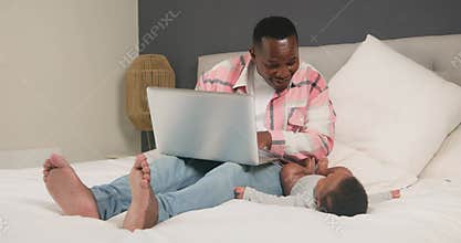 Working From Home Dad Multitasks with Baby on Bed: A Heartwarming Scene of Family and Career
