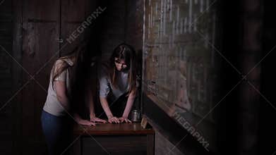Close-up of young people spinning discs on a wooden board in a dark quest room.