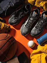Collection of Sports Gear Arranged With March Madness Flyer on an Orange Surface Highlighting the Excitement of the