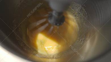 Eggs being rapidly beaten in stainless steel bowl of stand mixer