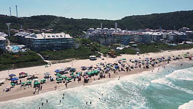 Panoramic and orbital drone aerial scene of a beach with many buildings and houses by the sea, luxury condominiums and resorts, cr