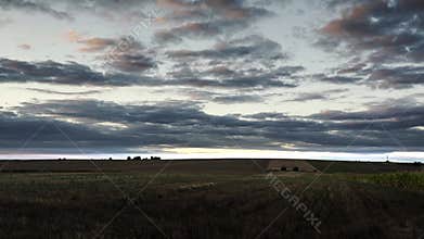 Expansive Field Landscape Under a Cloudy Sky During Sunset
