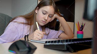 Girl is using computer for education. girl is studying remotely at home. girl in a white blouse is doing her homework on pc