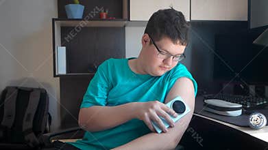 teenager man with diabetes checking blood glucose level at home using continuous glucose monitor. boy checks the glucose level
