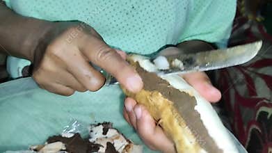 a woman's hand peels cassava skin
