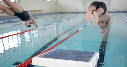 Swimmers diving into pool, competing in swimming race at indoor facility