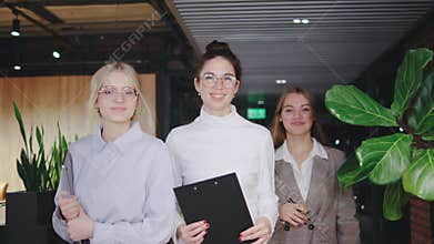 A group of Business women walking through the office collaborates with notebooks and clipboards, showcasing their