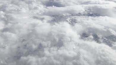 Aerial view of snow-covered mountains and fluffy clouds. Majestic mountain range, serene atmosphere,