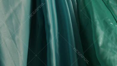 Closeup footage of a variety of green and blue silk fabrics in sunlight