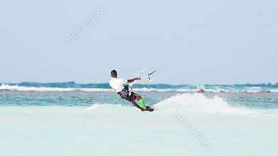 Indonesia, Maldives island, 03 December 2024: Tanned kitesurfer jumps on the water with splashes from under the board