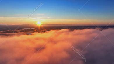 Drone flying over the clouds with a scenic sunset scene over the lakes on the horizon