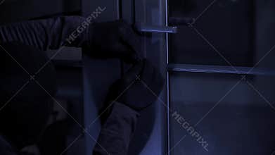 trespassing, theft male in balaclava with master key in hands opens door lock at night, close-up
