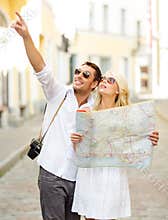 Smiling couple in sunglasses with map in the city