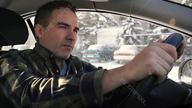 The driver carefully looks out the window at the road. In traffic jam. dark-haired man feeling thoughtful while standing