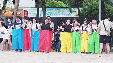 Nha Trang, Vietnam - 02 January, 2025: Asians stand in connected pants on the beach, faces painted with bright colors
