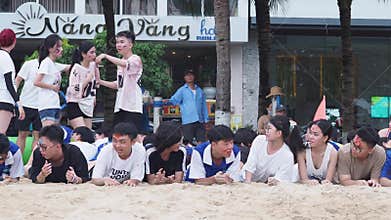 Nha Trang, Vietnam - 02 January, 2025: Asians with painted faces lie on the sand, laughing as they prepare for a beach