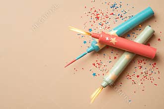 American flag-colored firecrackers, paper fans, and confetti are arranged in a flat lay on a blue background to convey
