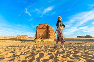 Tourist walking in the desert admiring Qasr Al Farid, the tomb of Lihyan son of Kuza in Hegra, Al Ula, Saudi Arabia