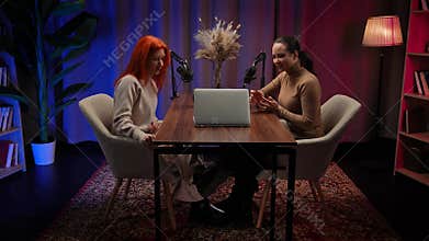 Two Influencers of women being interviewed in a loft-style podcast studio