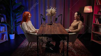 Two Influencers of women being interviewed in a loft-style podcast studio