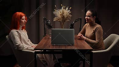 Two Influencers of women being interviewed in a loft-style podcast studio