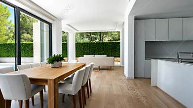 Bright and airy white kitchen interior with island, dining table, and large windows, creating a welcoming atmosphere