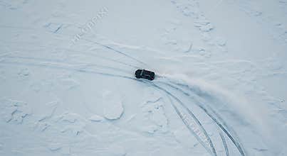 Car Drifting on Snowy Field Creating Track Marks From Above View
