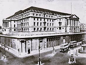 1930 black and white photo of the Bank of England, London, showcasing its classical architecture and surrounding street traffic.
