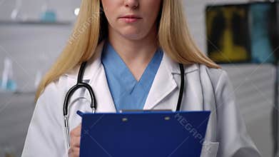 Female Doctor Writing on Blue Clipboard in Hospital Setting