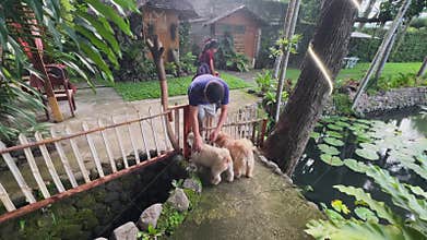 Man lifts lapdog into arms while lady strolls with dachshund