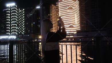 A woman captures urban beauty at night, showcasing stunning scenes