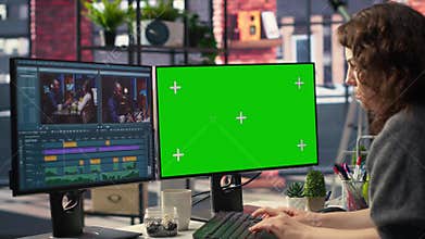 Female videographer making a movie montage next to green screen display