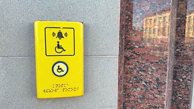Yellow call button with wheelchair symbol and braille for accessibility assistance