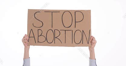 Female person holds up cardboard sign with words Stop Abortion