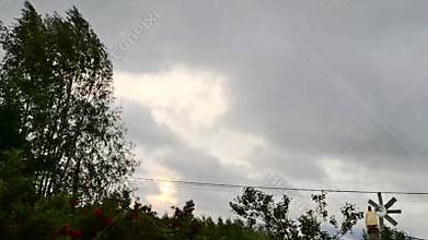 Windy weather with moving clouds and trees in a rural landscape.